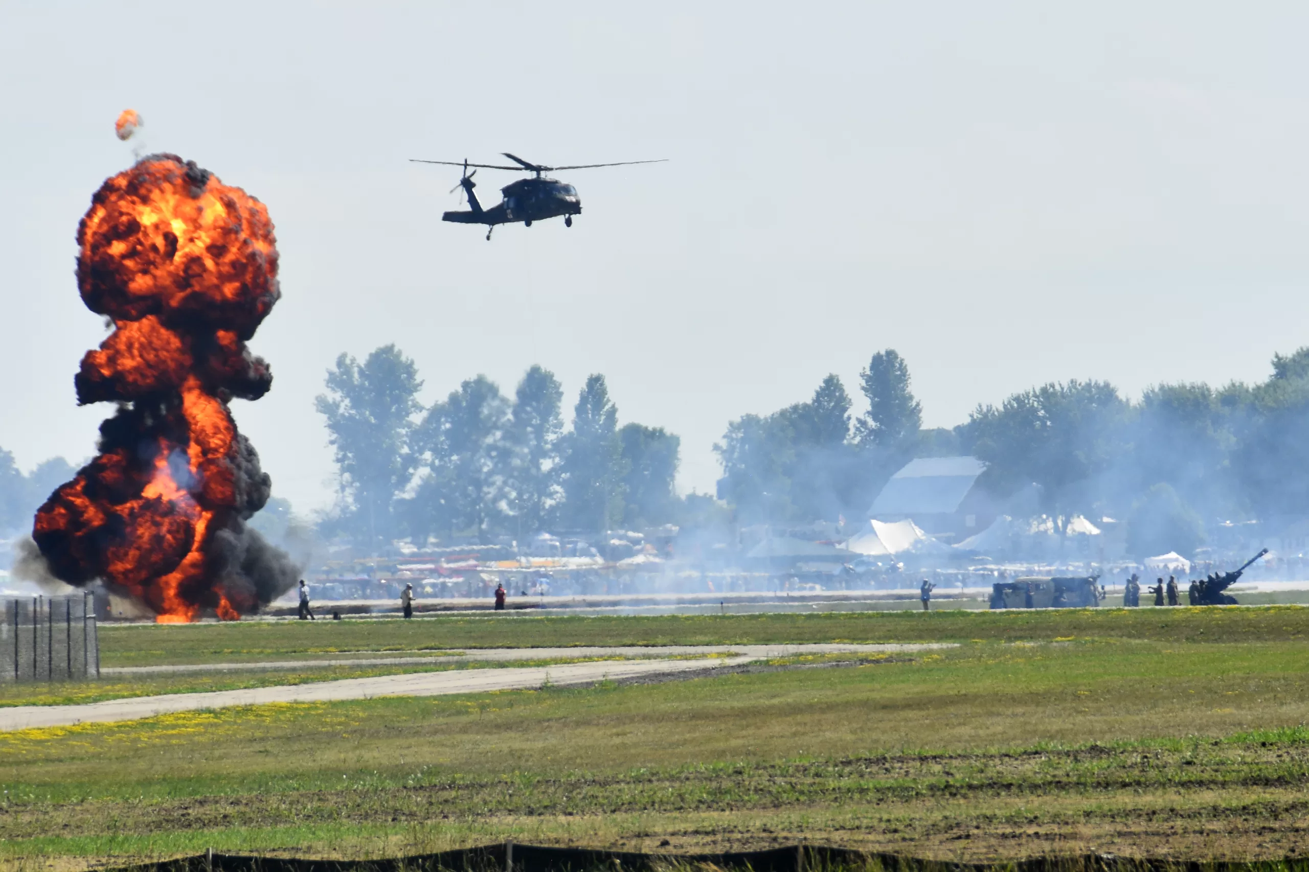 A UH-60 Black Hawk helicopter from the Wisconsin Army National Guard’s 1st Battalion, 147th Aviation Regiment moves past a burst of ground pyrotechnics at Wittman Regional Airport July 28 as part of a Wisconsin National Guard warfighting capabilities demonstration during the Experimental Aircraft Association’s AirVenture in Oshkosh, Wis. The demonstration included the F-35 Lightning fighter jet from the 115th Fighter Wing, a KC-135 Stratotanker from the 128th Air Refueling Wing, UH-60 Black Hawk helicopters from the 1st Battalion, 147th Aviation Regiment performing an air assault with Soldiers from the 2nd Battalion, 127th Infantry Regiment as well as a medevac patient hoist, and 105-mm howitzer firing demonstrations by members of the 1st Battalion, 120th Field Artillery Regiment. Pyrotechnics on the ground and narration by EAA staff made the demonstration even more memorable for EAA attendees. Wisconsin Department of Military Affairs photo by Vaughn R. Larson